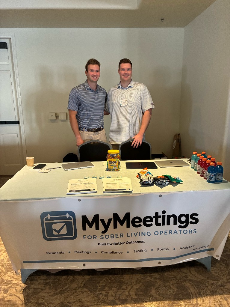 Nick on the left and Jack on the right standing behind a table at the NSLA conference in Las Vegas